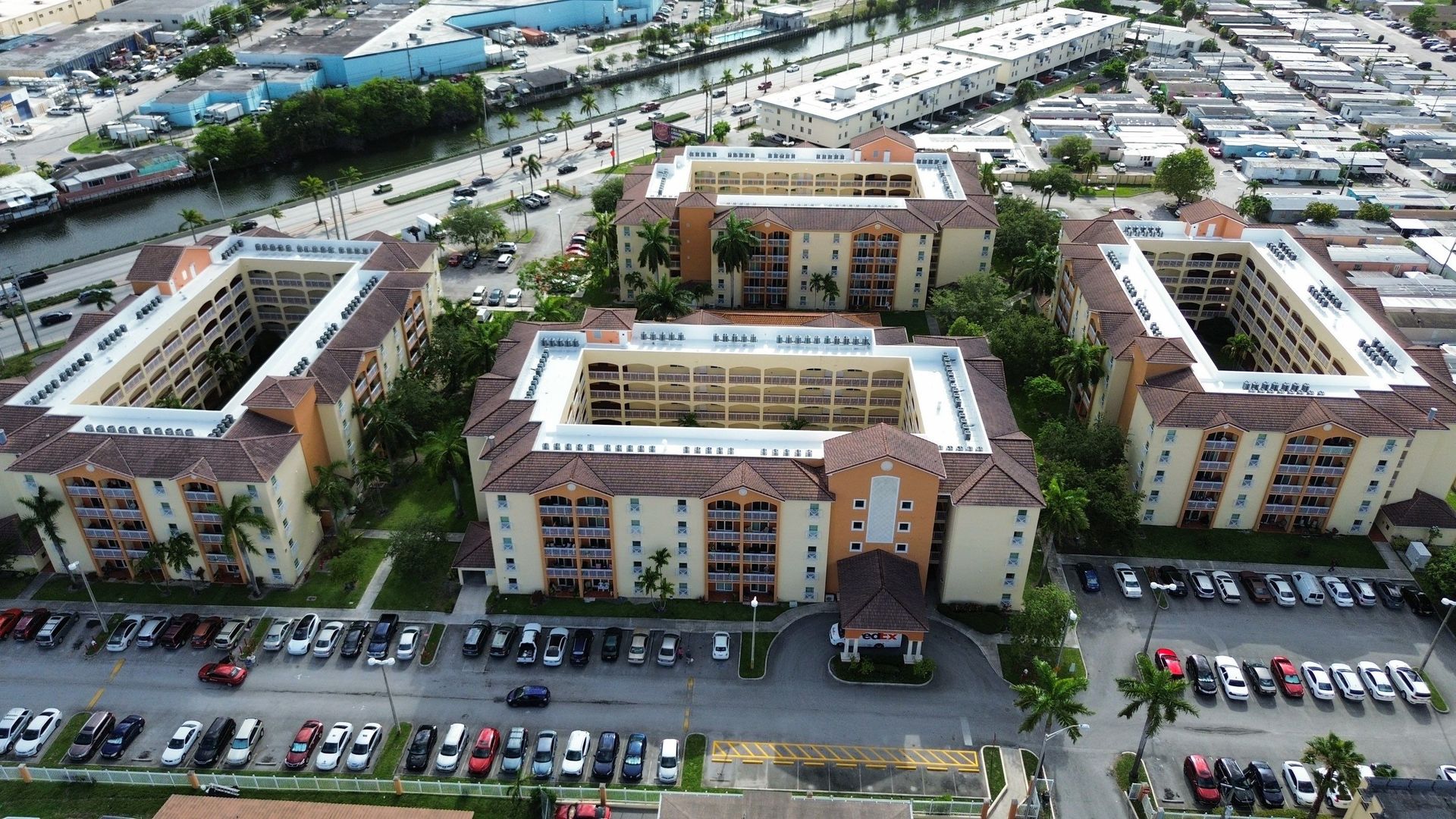 Aerial view of a modern apartment complex with parking lots and surrounding buildings
