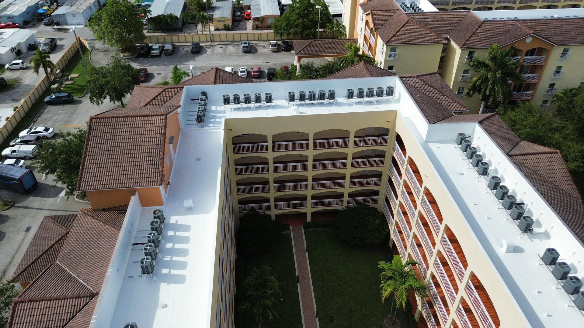 Aerial view of a white apartment building with red roofs and an inner courtyard in a residential area