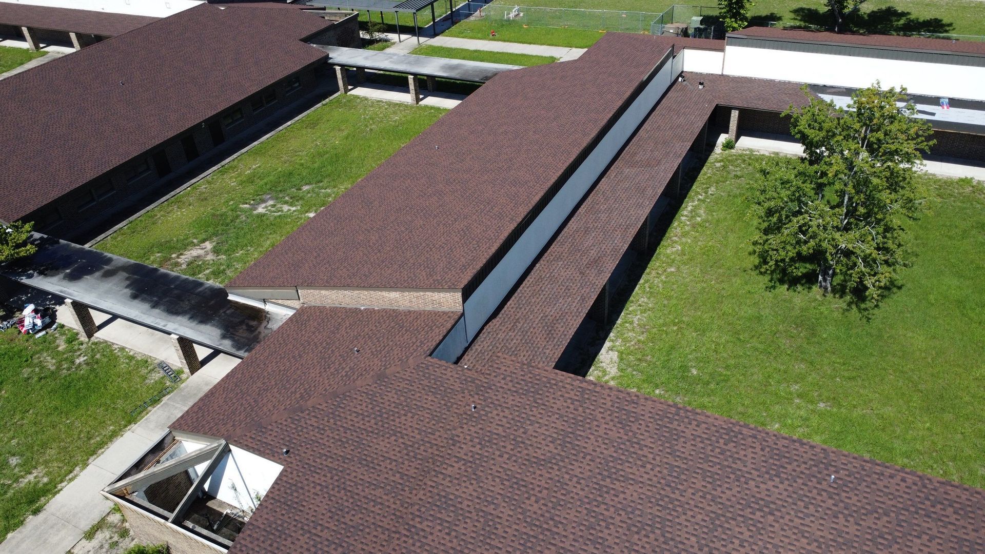 Aerial view of brown-roofed buildings surrounding a grassy courtyard and walkway.