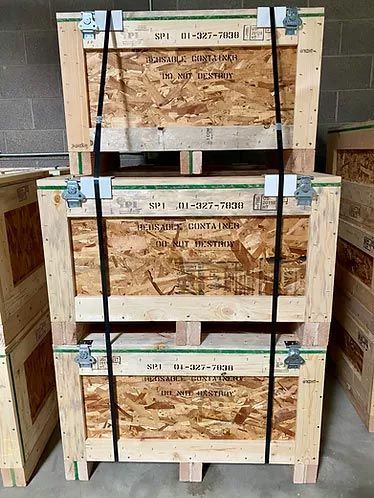 Three wooden crates are stacked on top of each other in a warehouse.