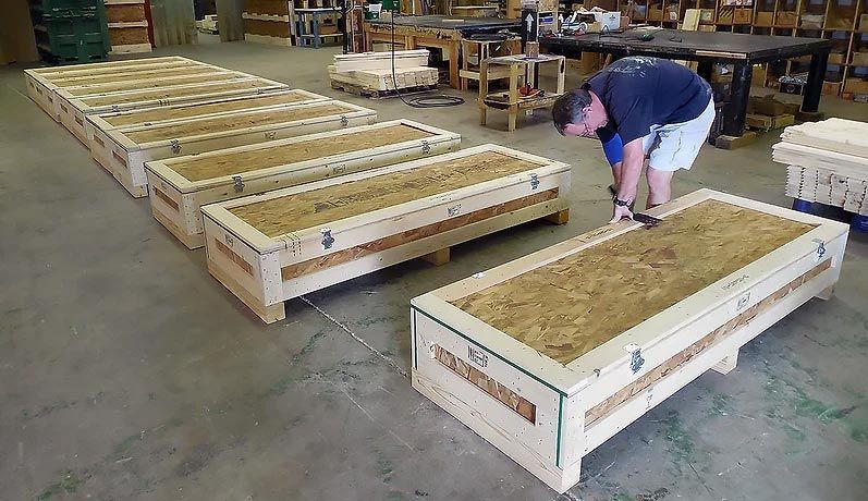 A man is working on a wooden box in a factory.