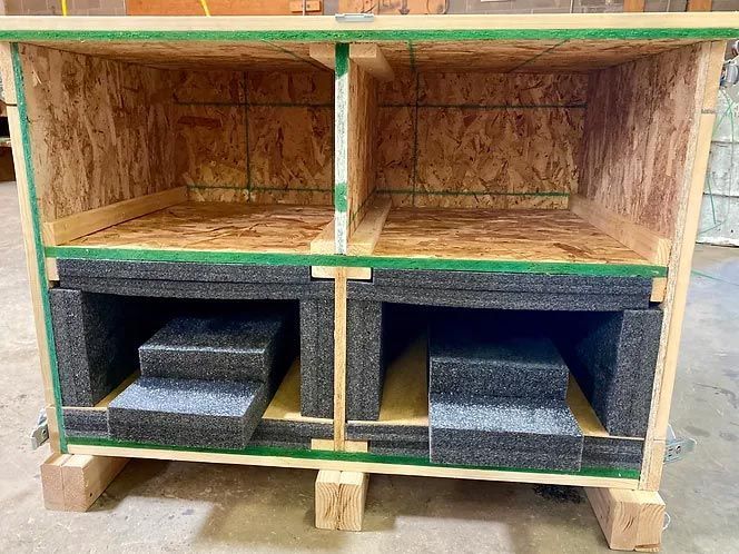 A wooden box with foam in it is sitting on a concrete floor.