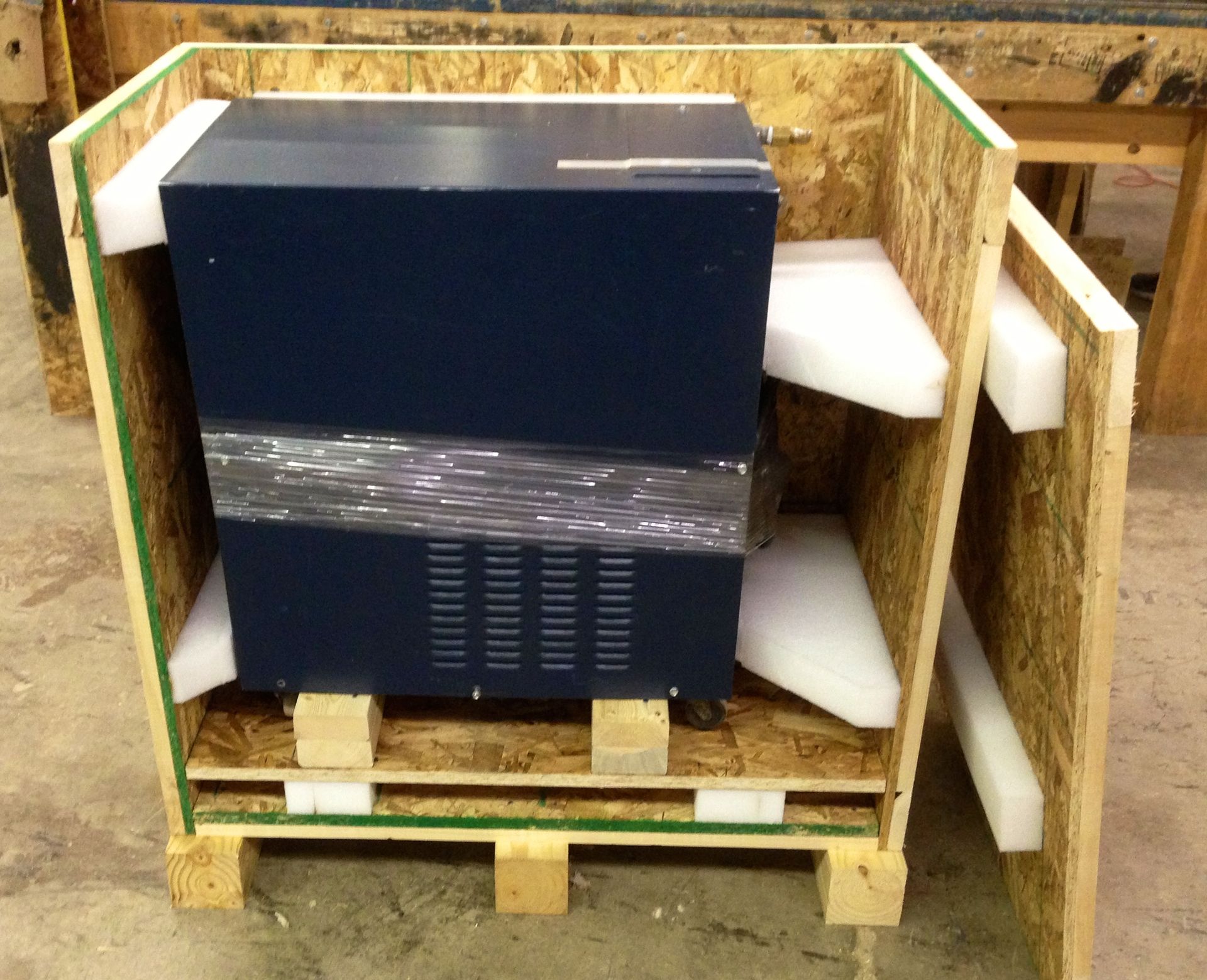 A black box is wrapped in plastic in a wooden crate