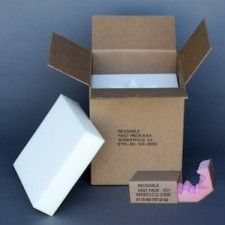 Cardboard box open with foam inserts, small box with pink packing material, and separate foam block.