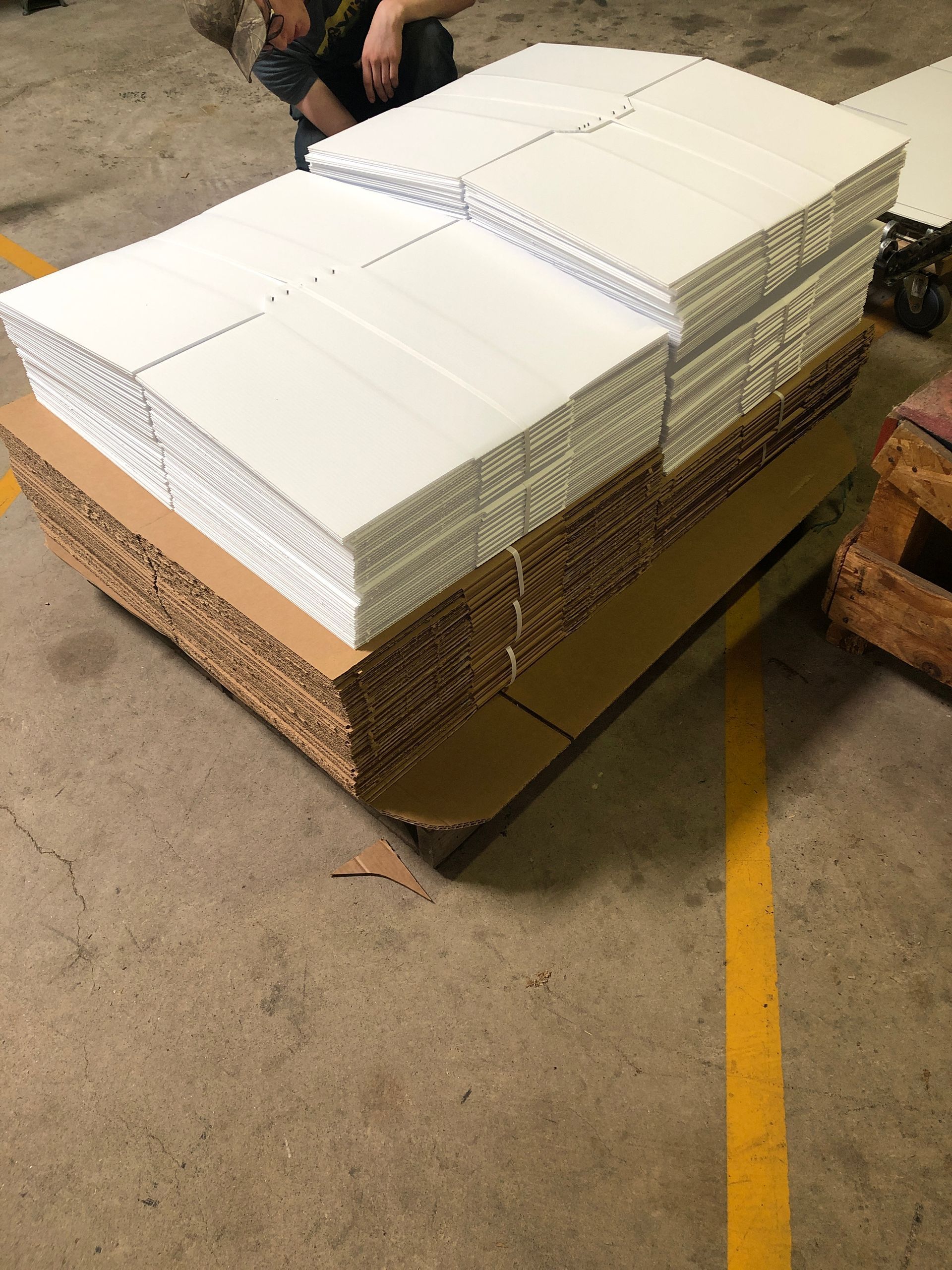 A large stack of paper is sitting on top of a cardboard box.
