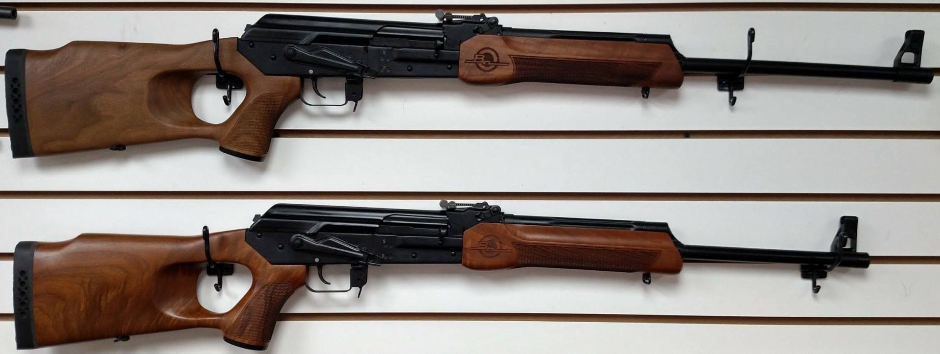two assault rifles are hanging on a white wall