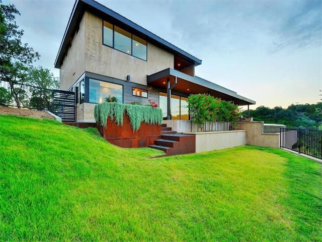 A large house is sitting on top of a lush green hillside.