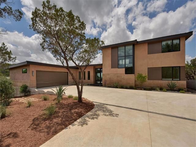 A house with a driveway and a tree in front of it.