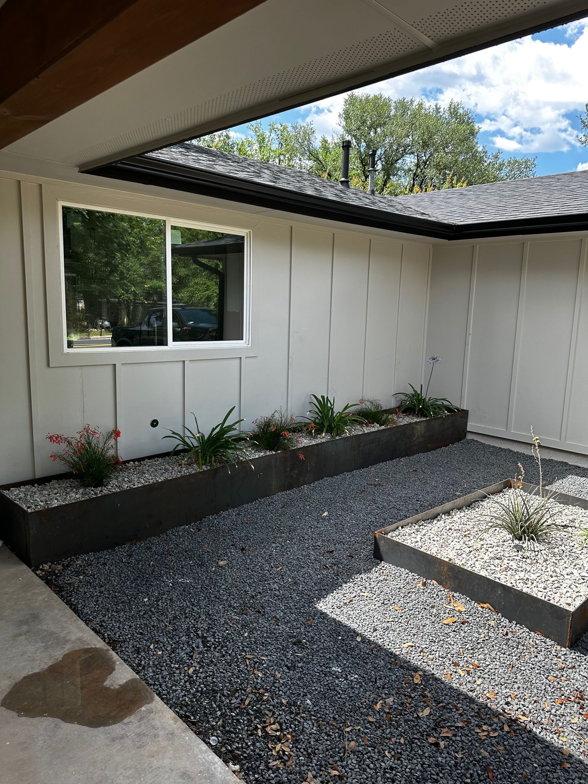 A white house with a gravel yard in front of it.
