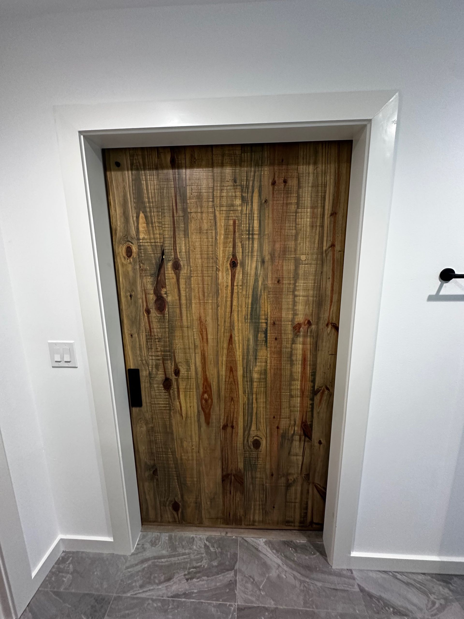 A wooden door is sitting in a hallway next to a white wall.