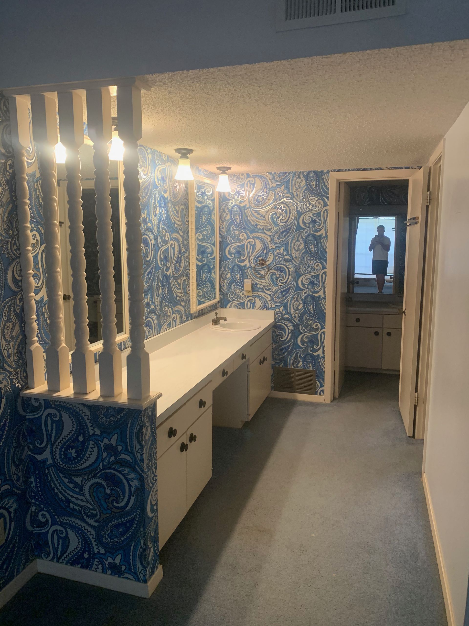 A bathroom with blue and white wallpaper and a sink.