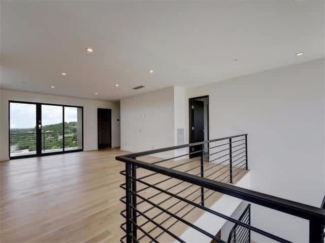 An empty room with a black railing and sliding glass doors.