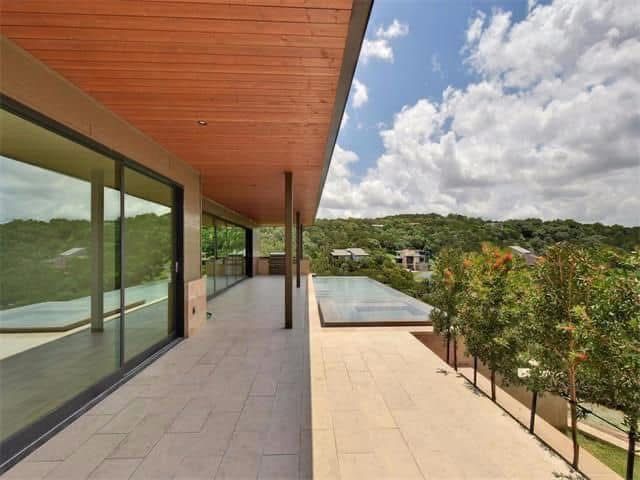 A balcony with a view of a swimming pool and trees.