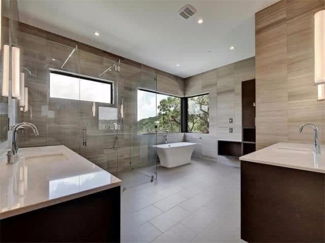 A bathroom with two sinks, a tub, and a walk in shower.