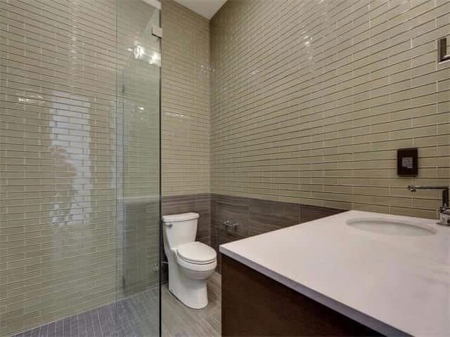A bathroom with a toilet, sink, and walk in shower.