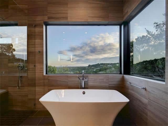 A bathroom with a bathtub and a large window.
