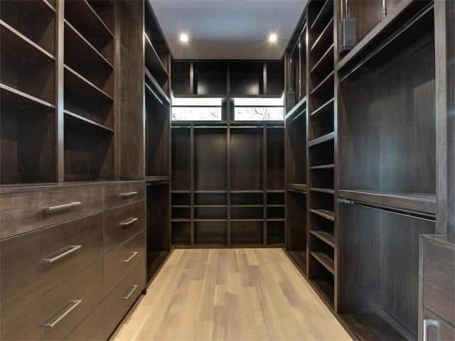 A walk in closet with lots of shelves and drawers.