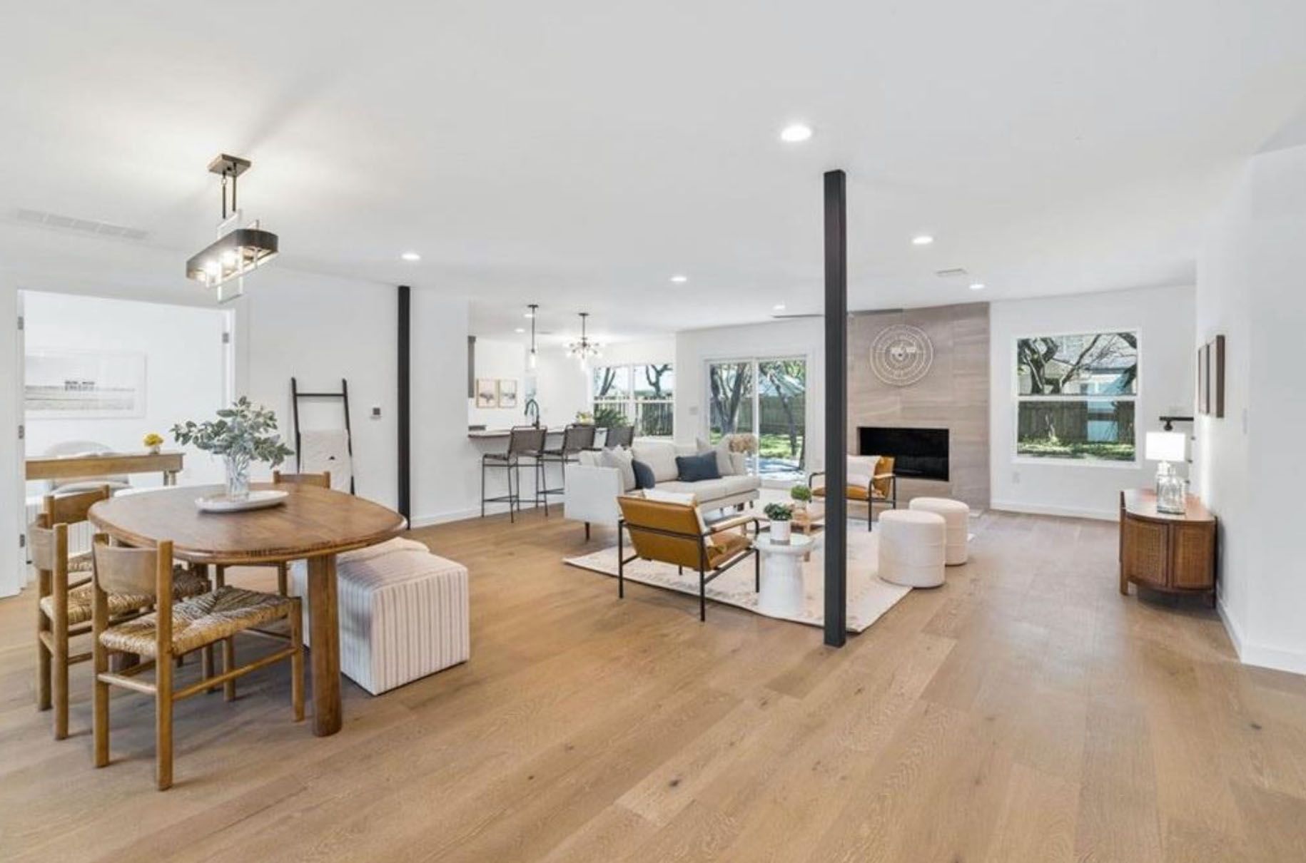 A living room with hardwood floors, a table and chairs, and a fireplace.
