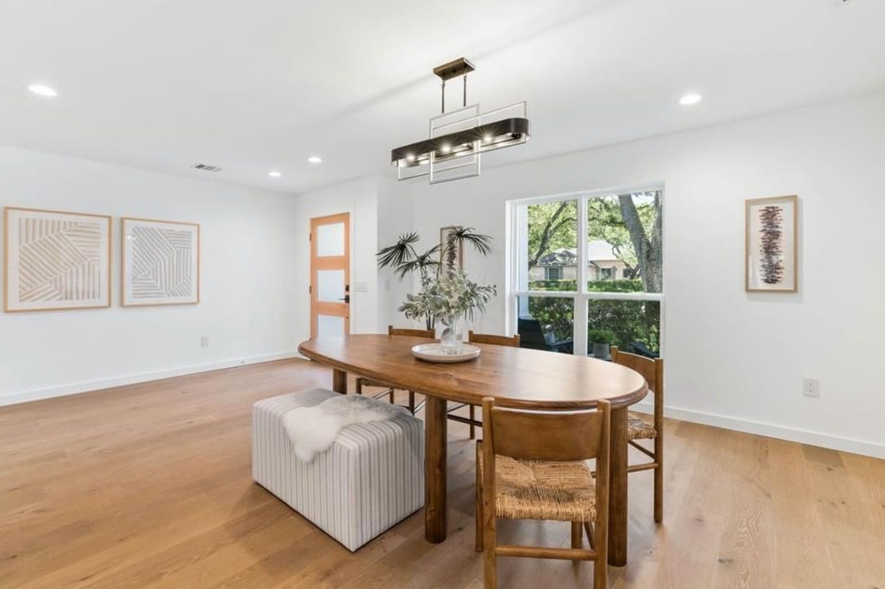 A dining room with a wooden table and chairs and a large window.