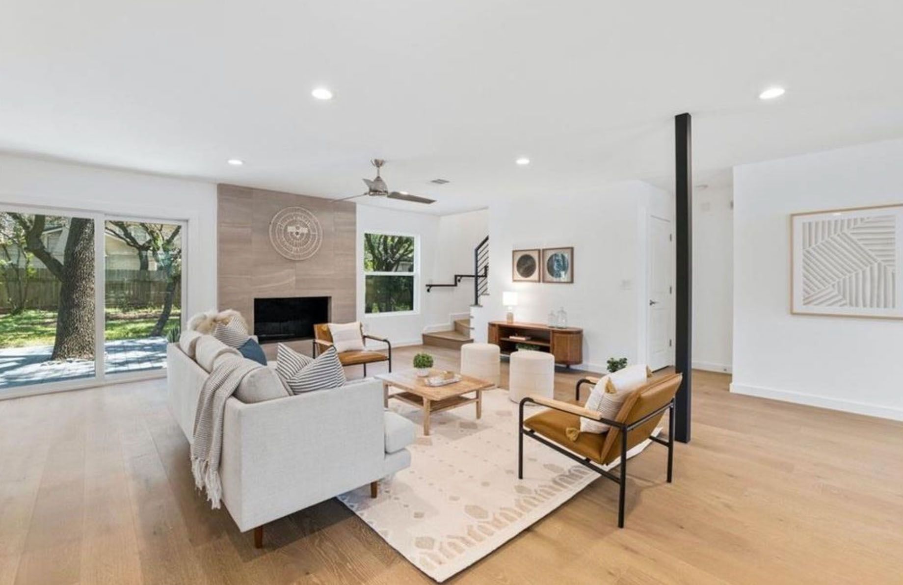 A living room with a couch, chairs, coffee table and fireplace.