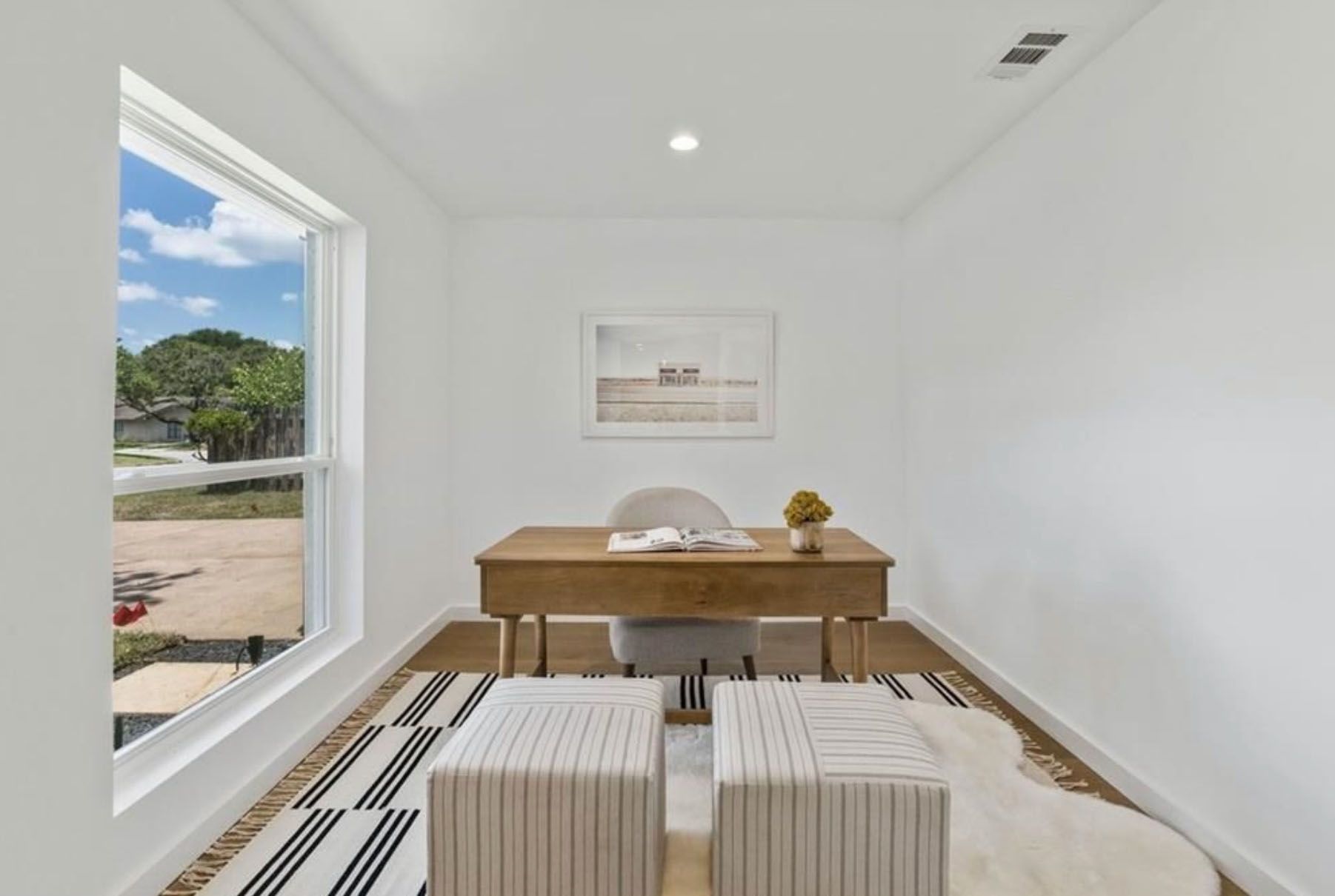 A room with a desk and two ottomans in it.