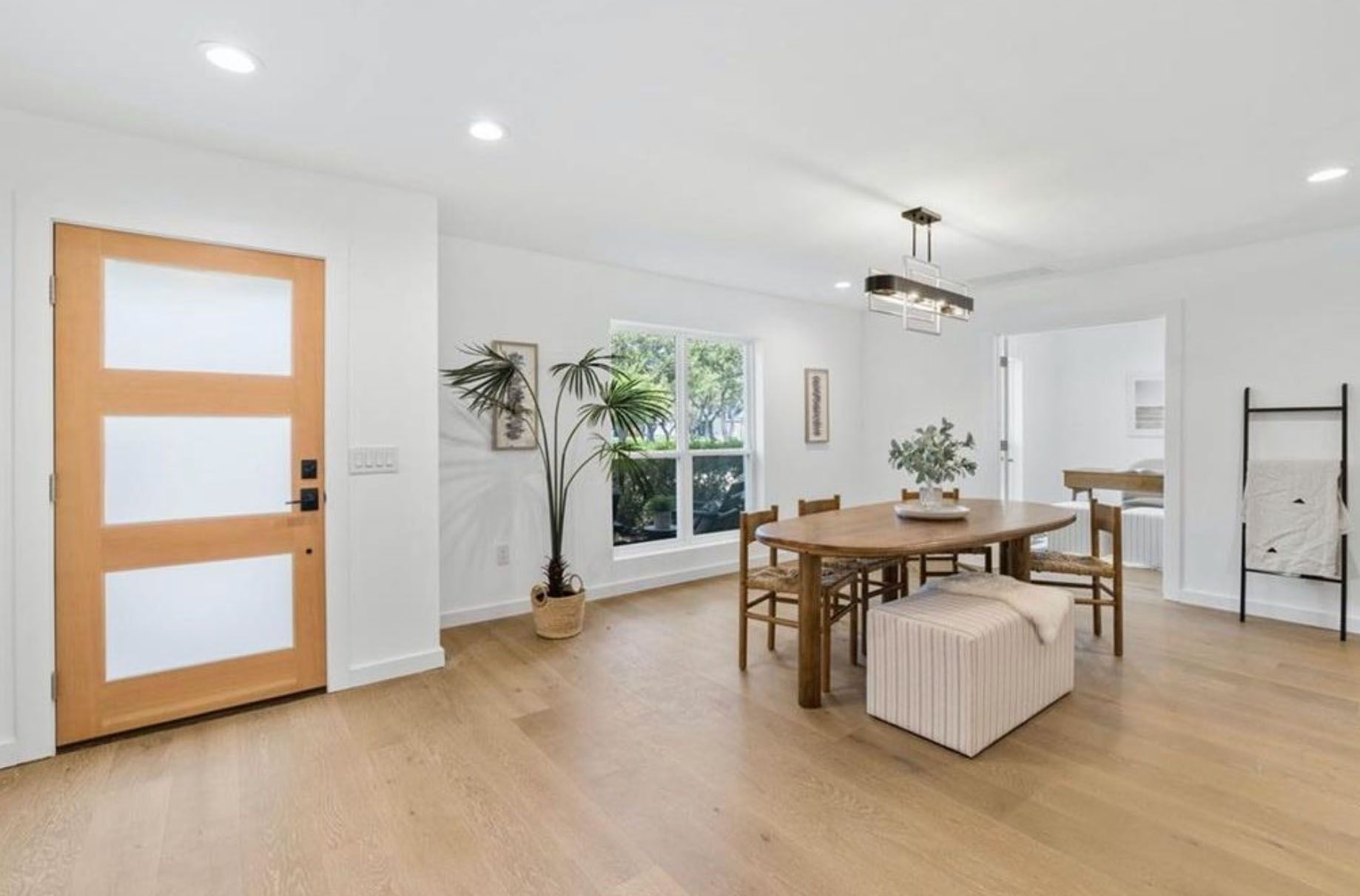 A living room with a wooden table and chairs and a wooden door.