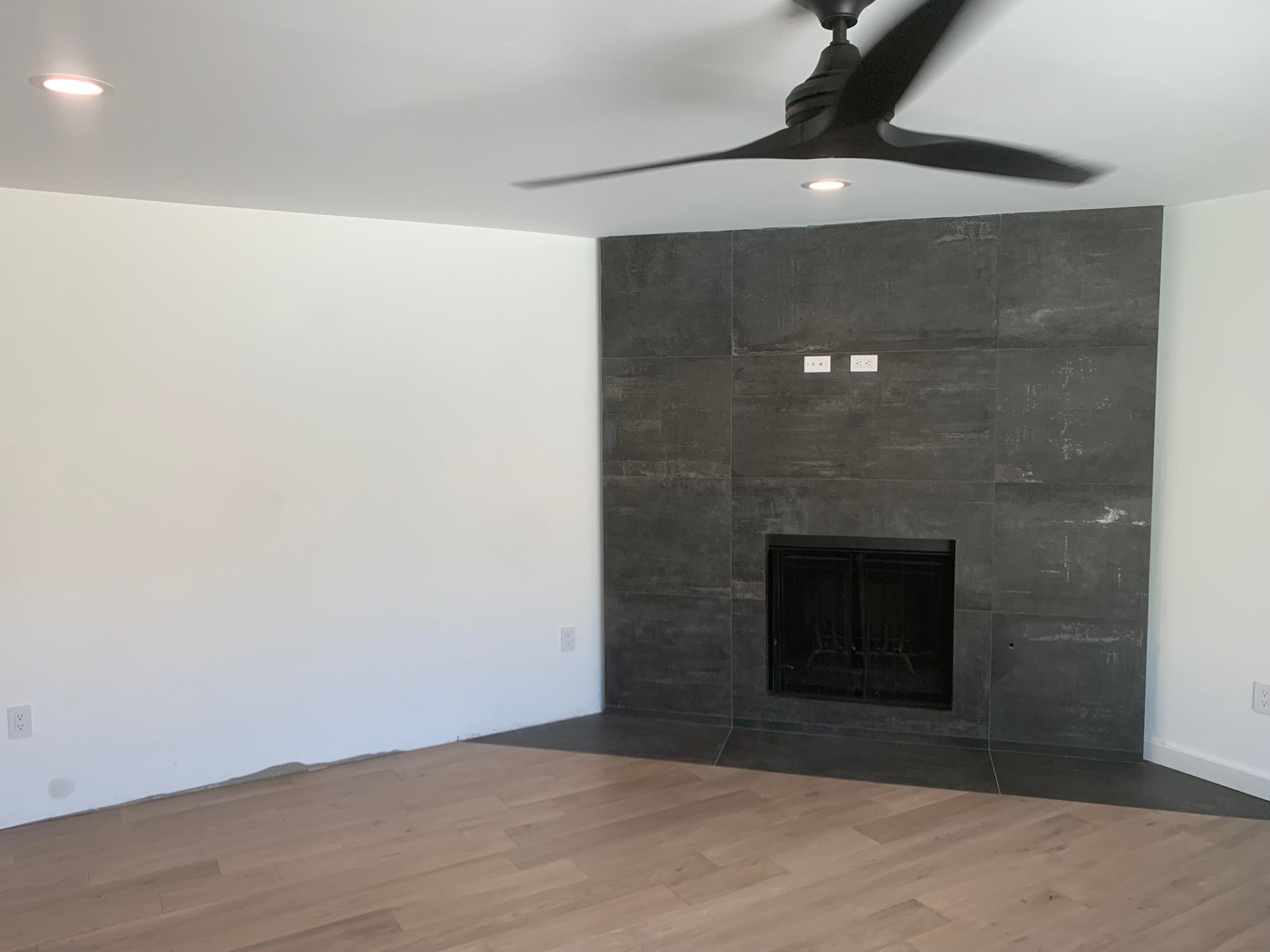 A living room with a fireplace and a ceiling fan.