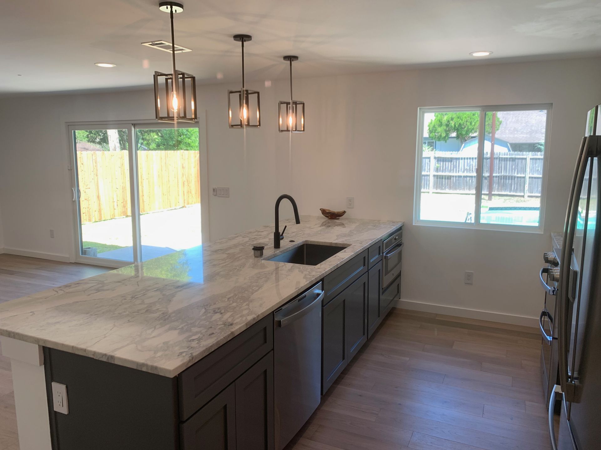 A kitchen with stainless steel appliances, granite counter tops, and a large island.