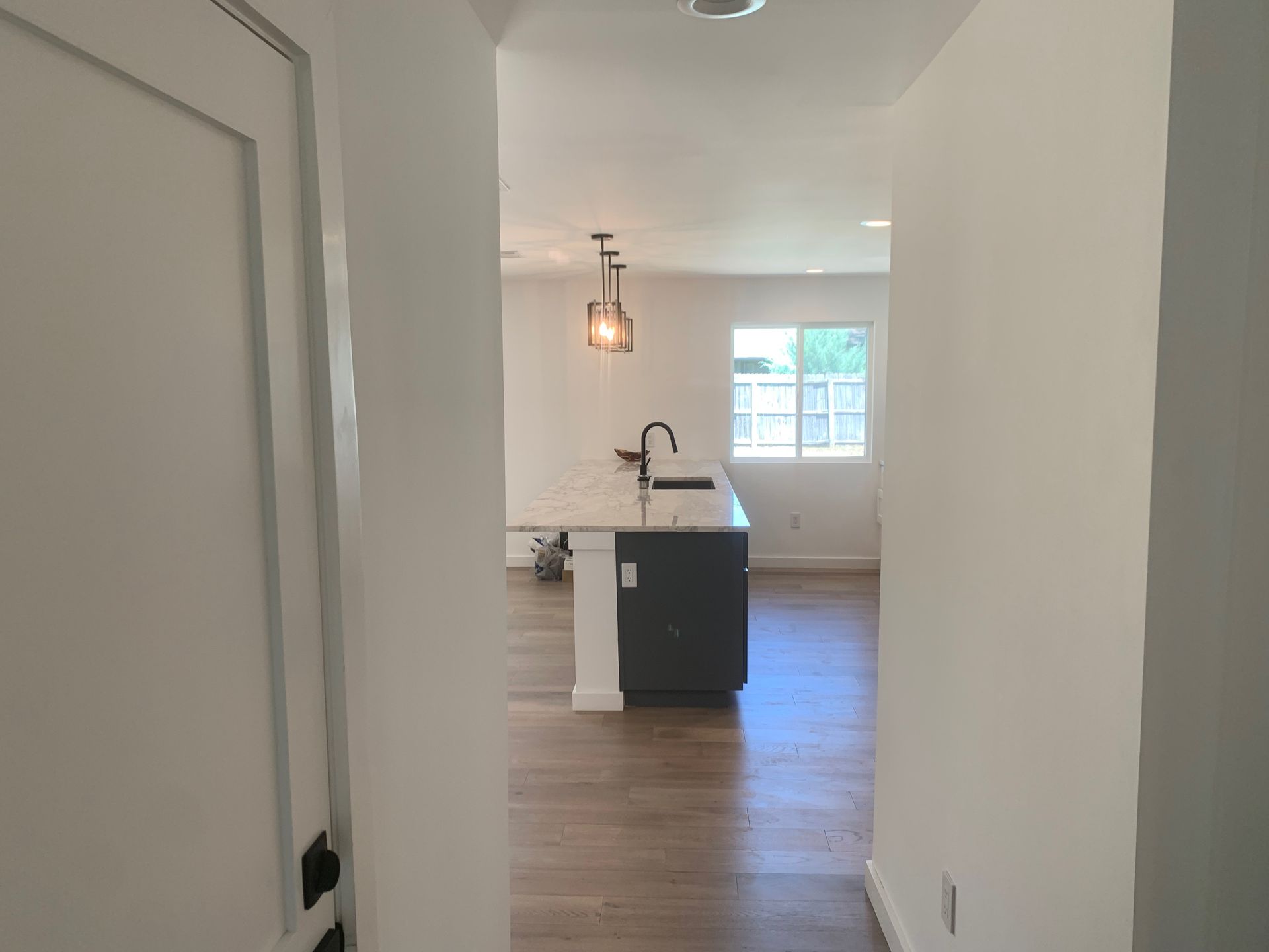 A hallway leading to a kitchen with a sink and a window.