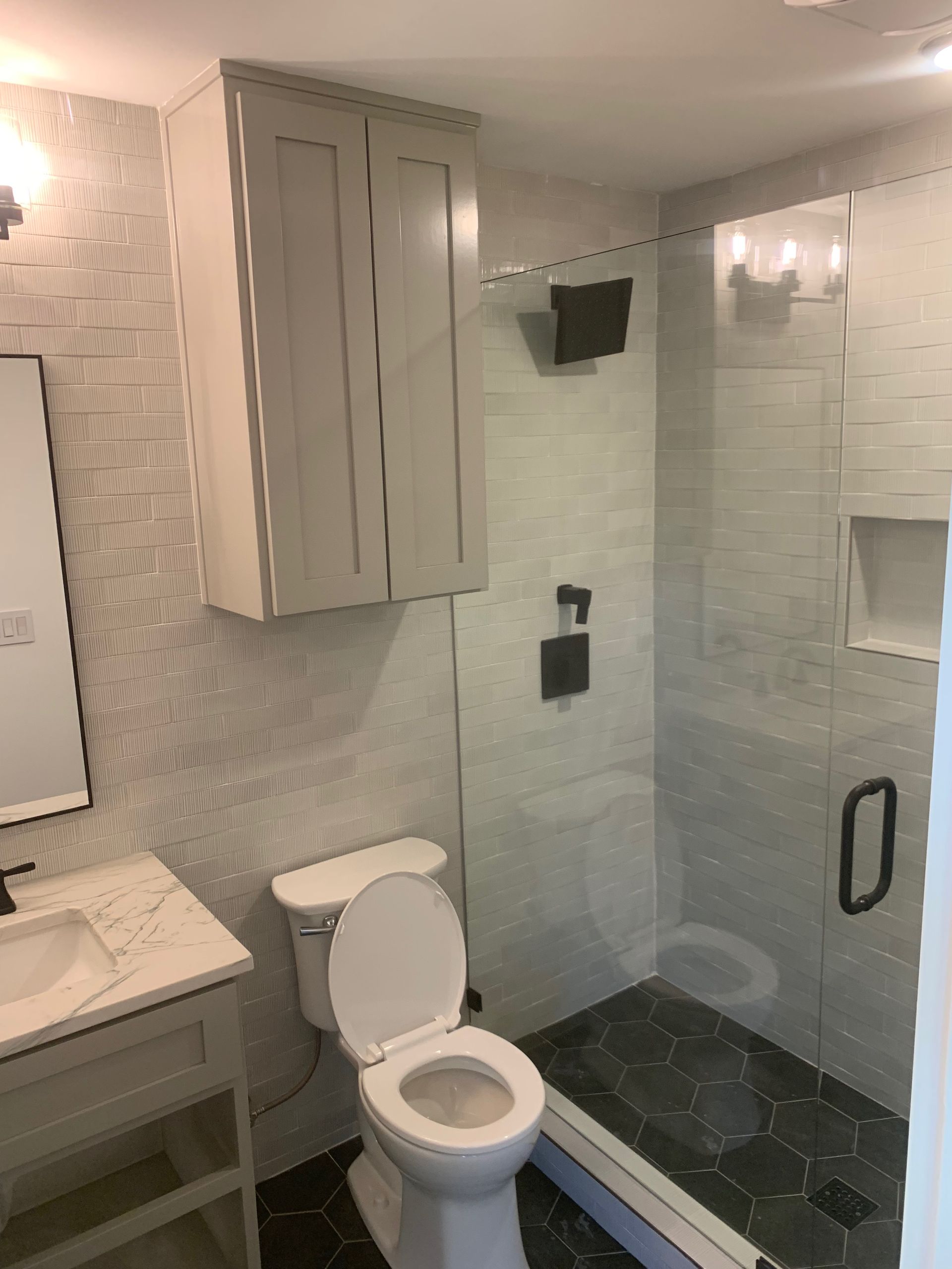 A bathroom with a toilet, sink, mirror, and shower.
