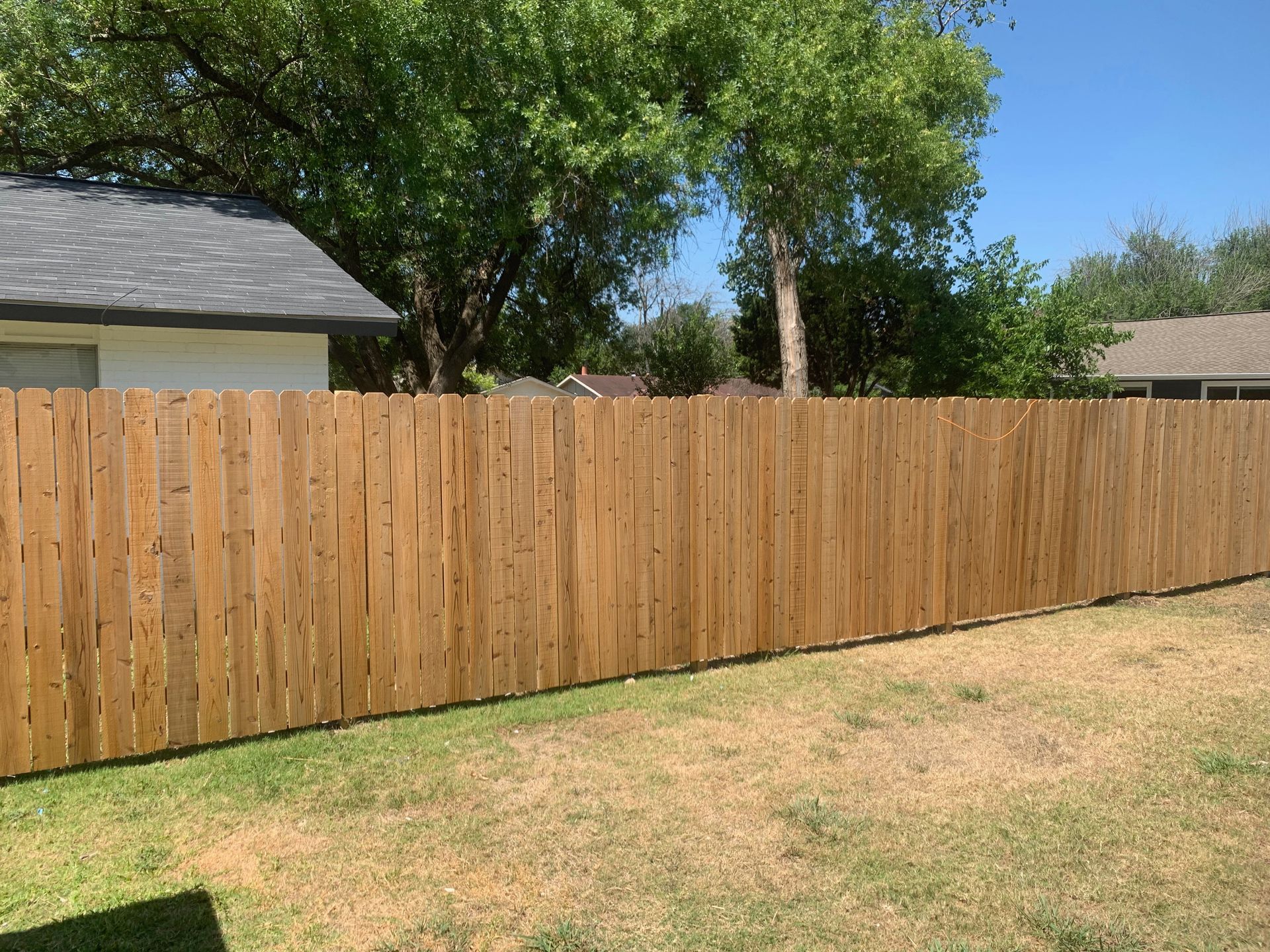 A wooden fence is in the backyard of a house.