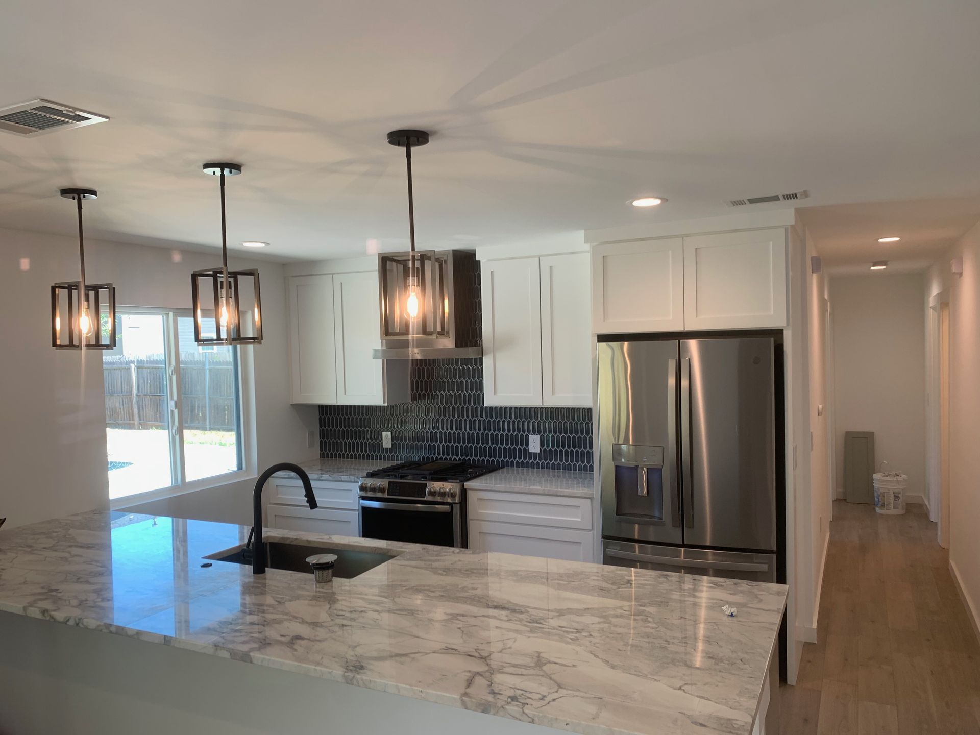 A kitchen with white cabinets, granite counter tops, stainless steel appliances, and a refrigerator.