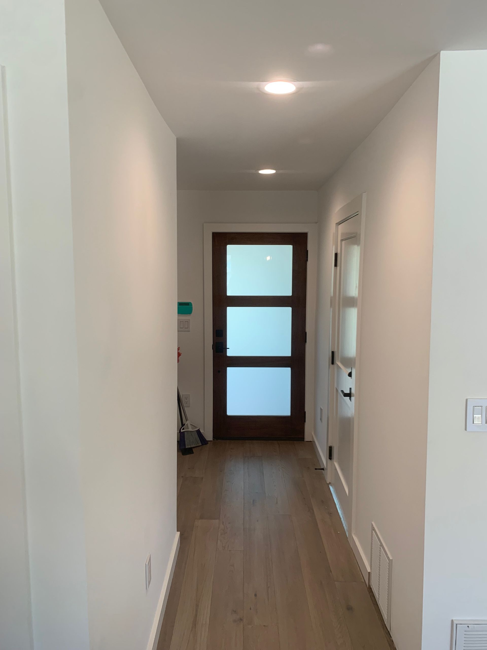A hallway with a wooden door and white walls.