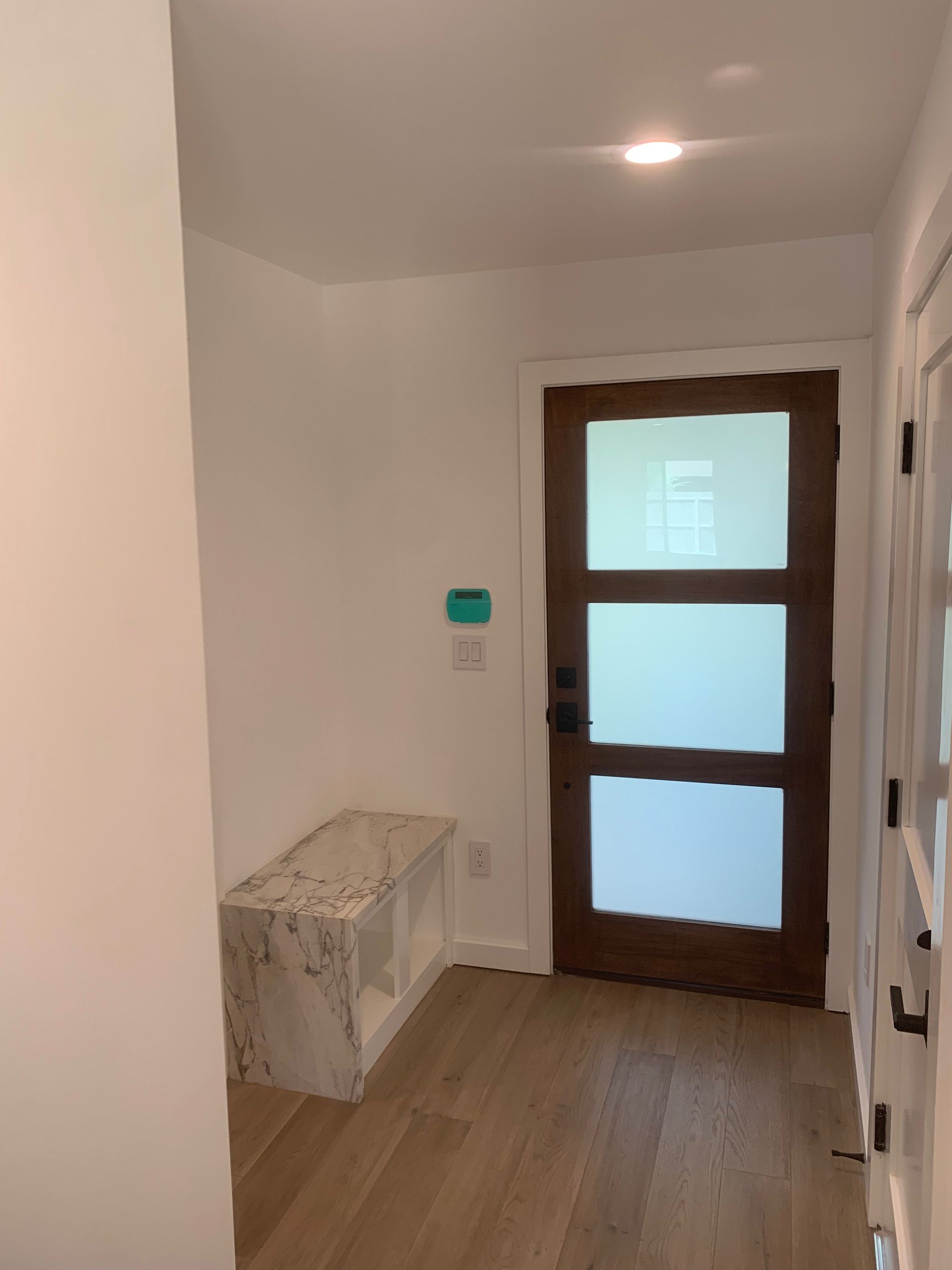 A hallway with a wooden door and a bench.