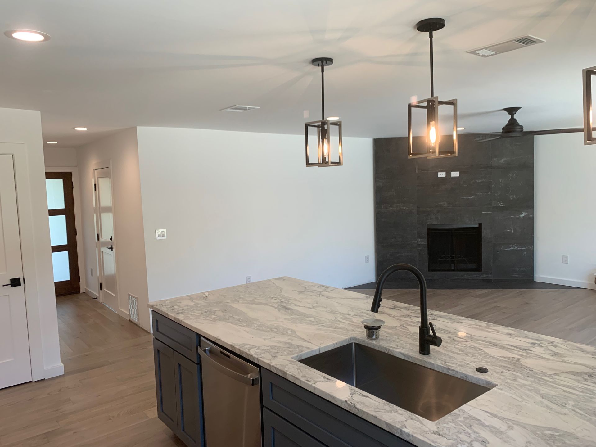 A kitchen with a sink and a fireplace in the background.