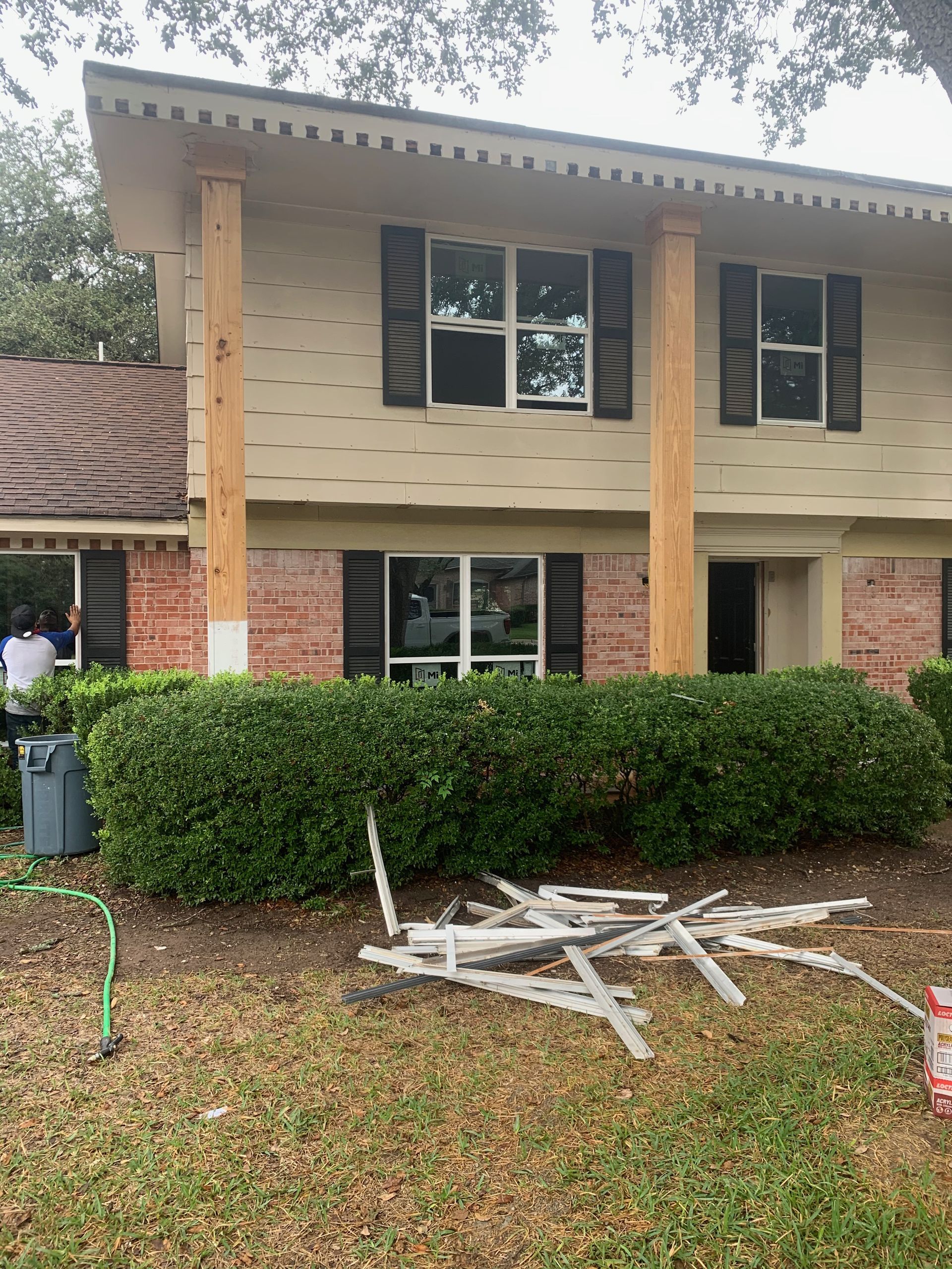 A brick house with black shutters is being painted.