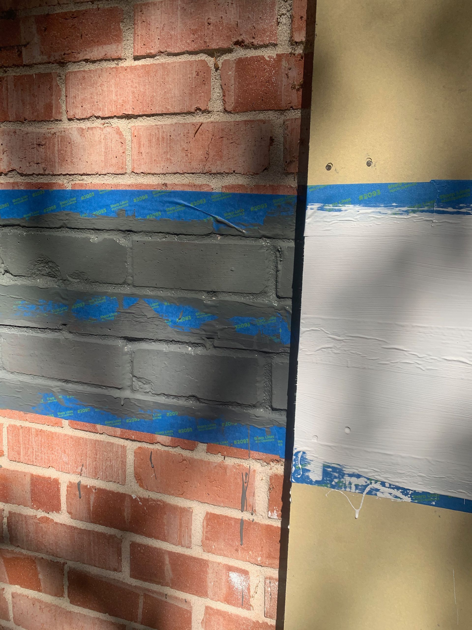 A brick wall with a blue and white tape on it.