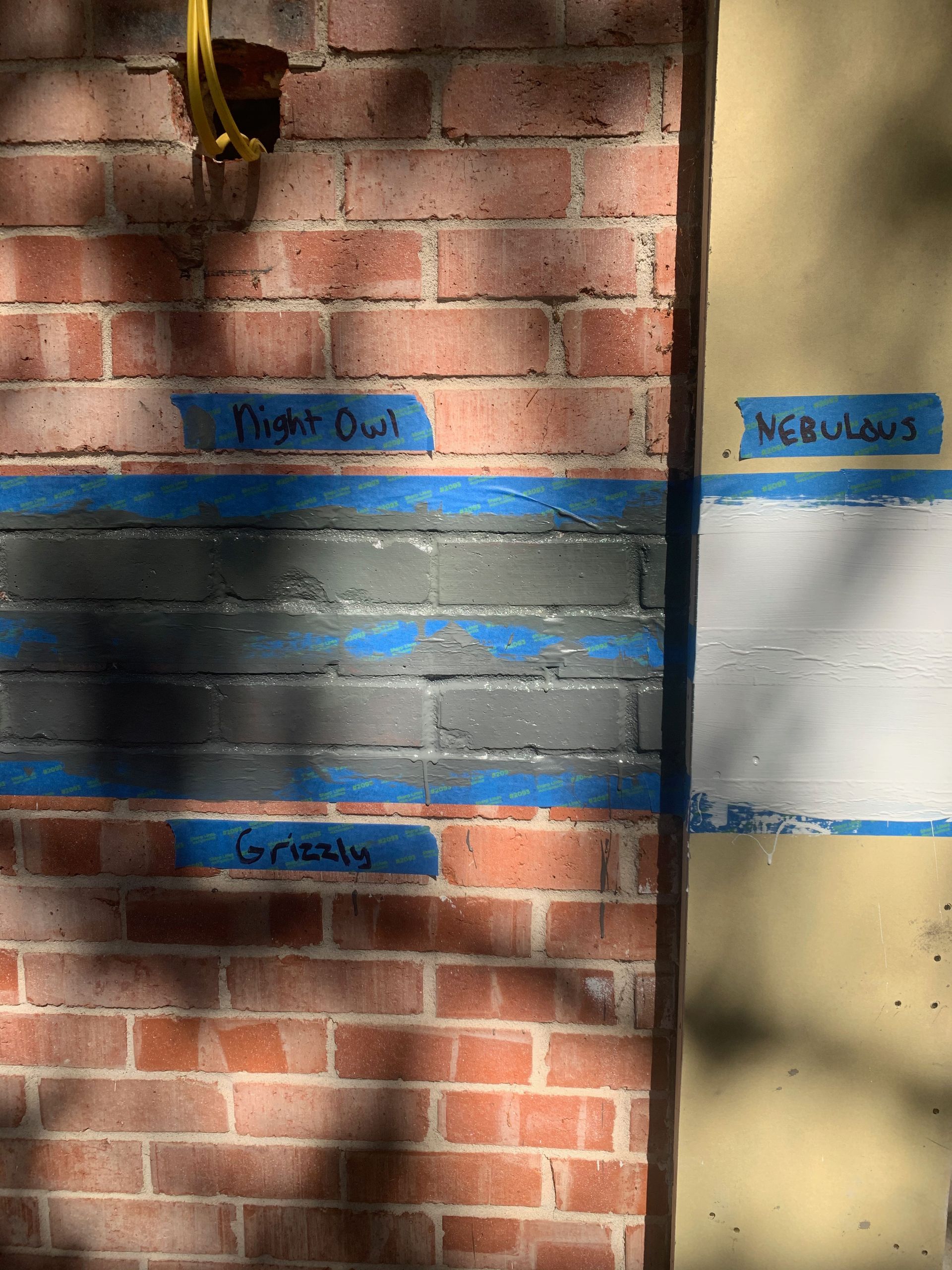 A close up of a brick wall with blue tape on it.