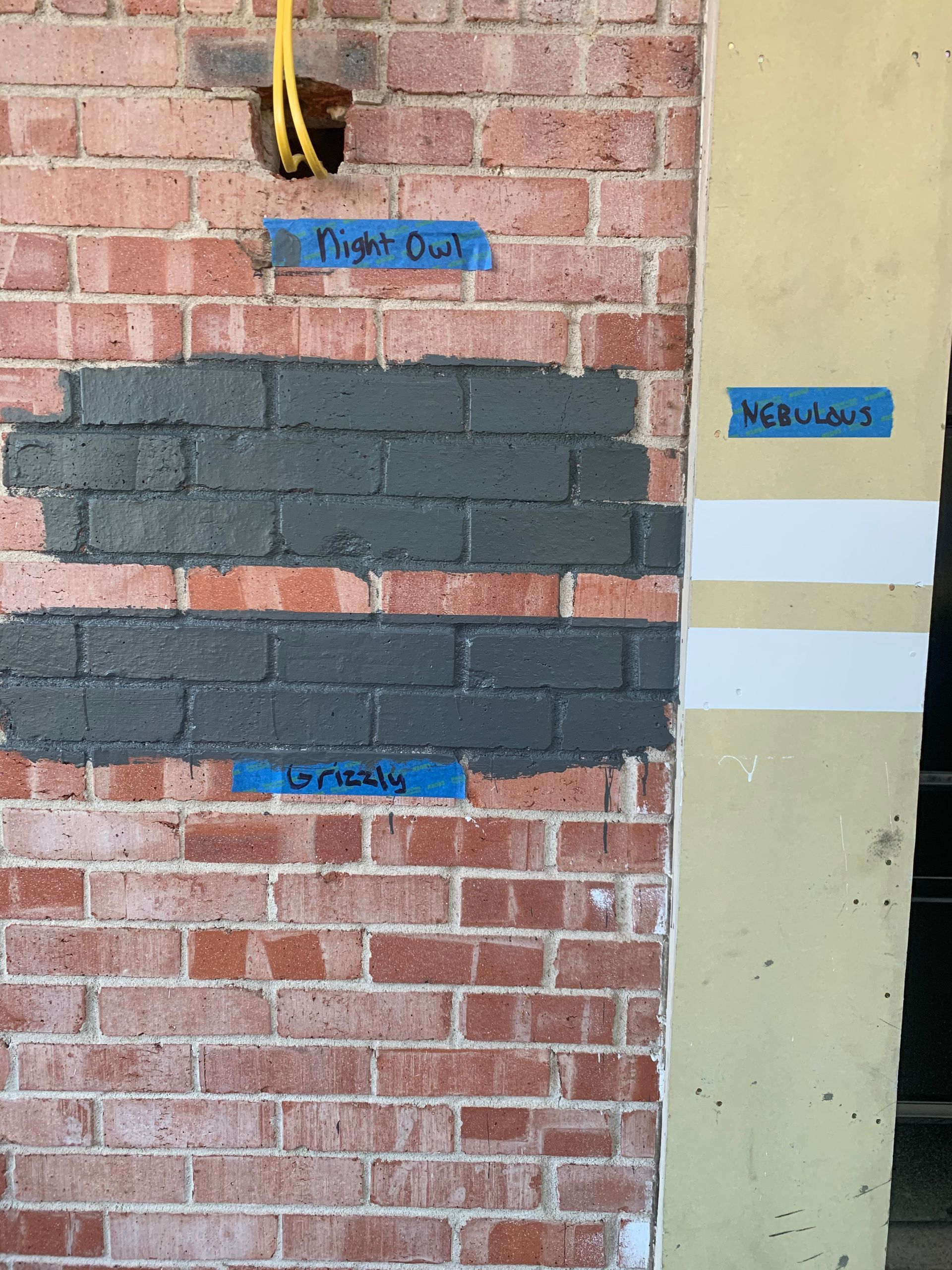 A brick wall with three different shades of paint on it.