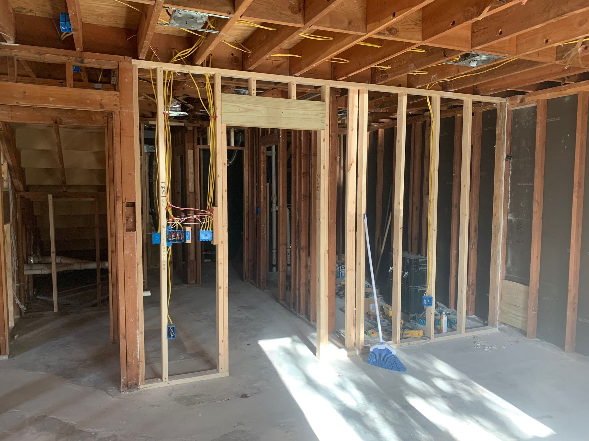 A room in a house under construction with wooden beams and a broom.
