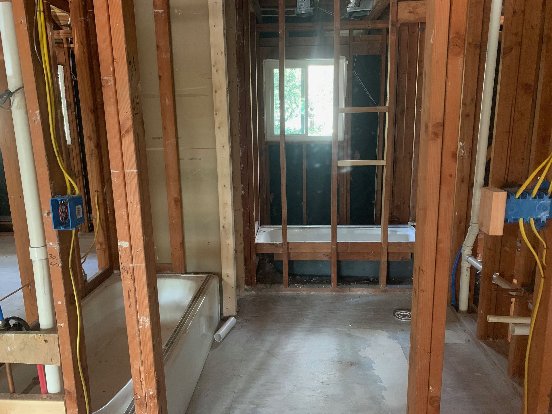 A bathroom under construction with a bathtub and a window.