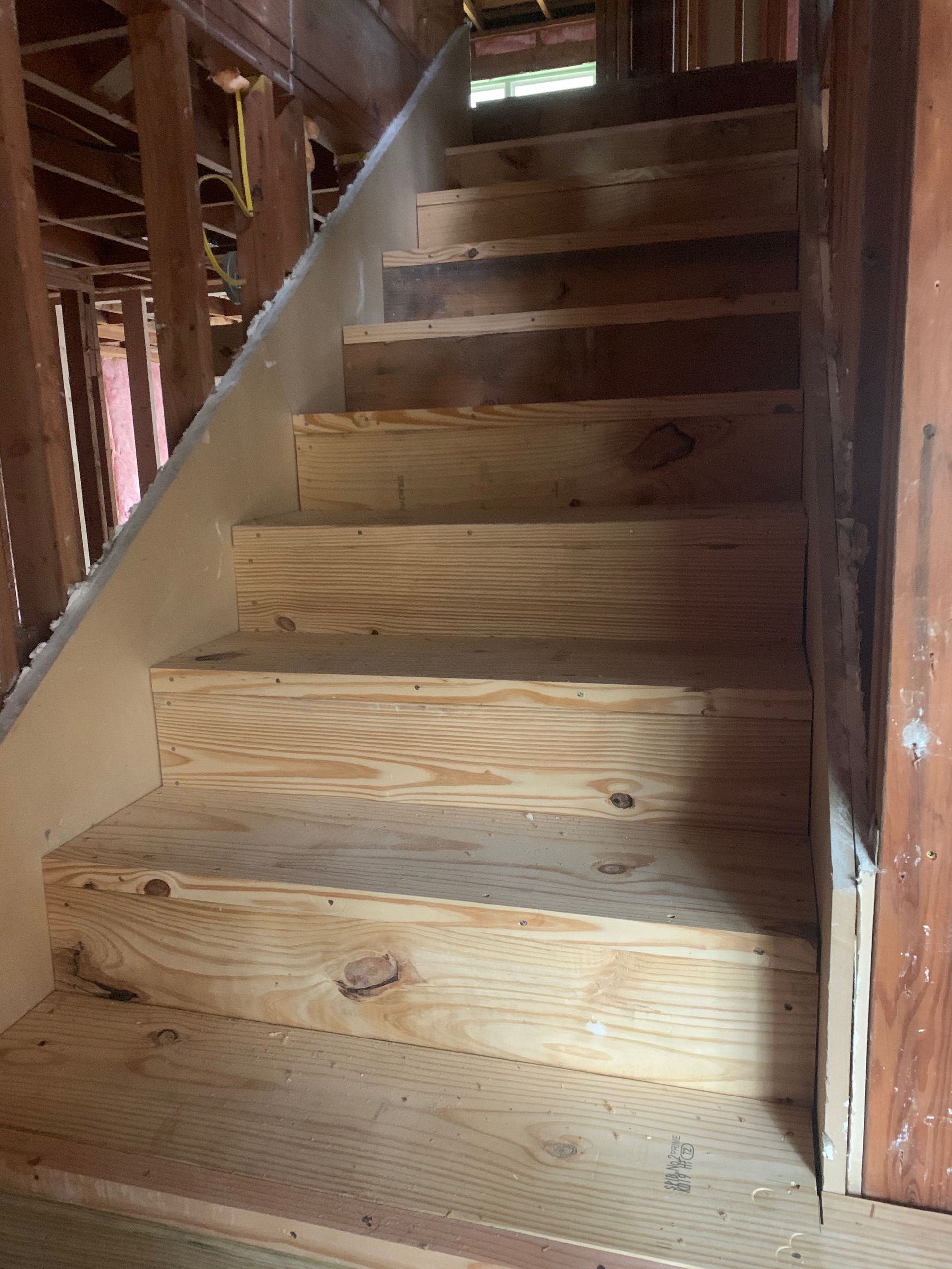 A wooden staircase is being built in a house.