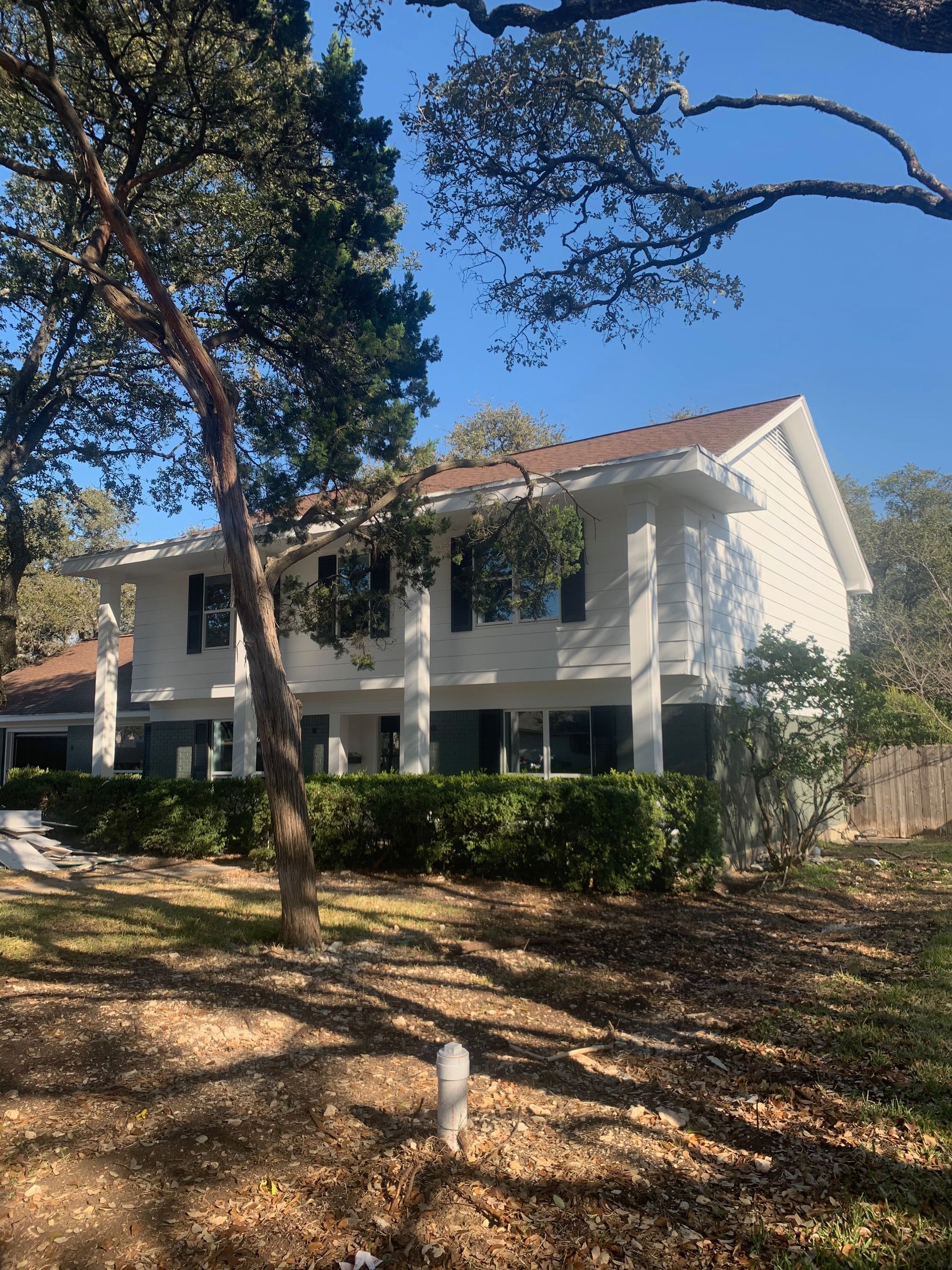 A white house with a red roof is surrounded by trees.