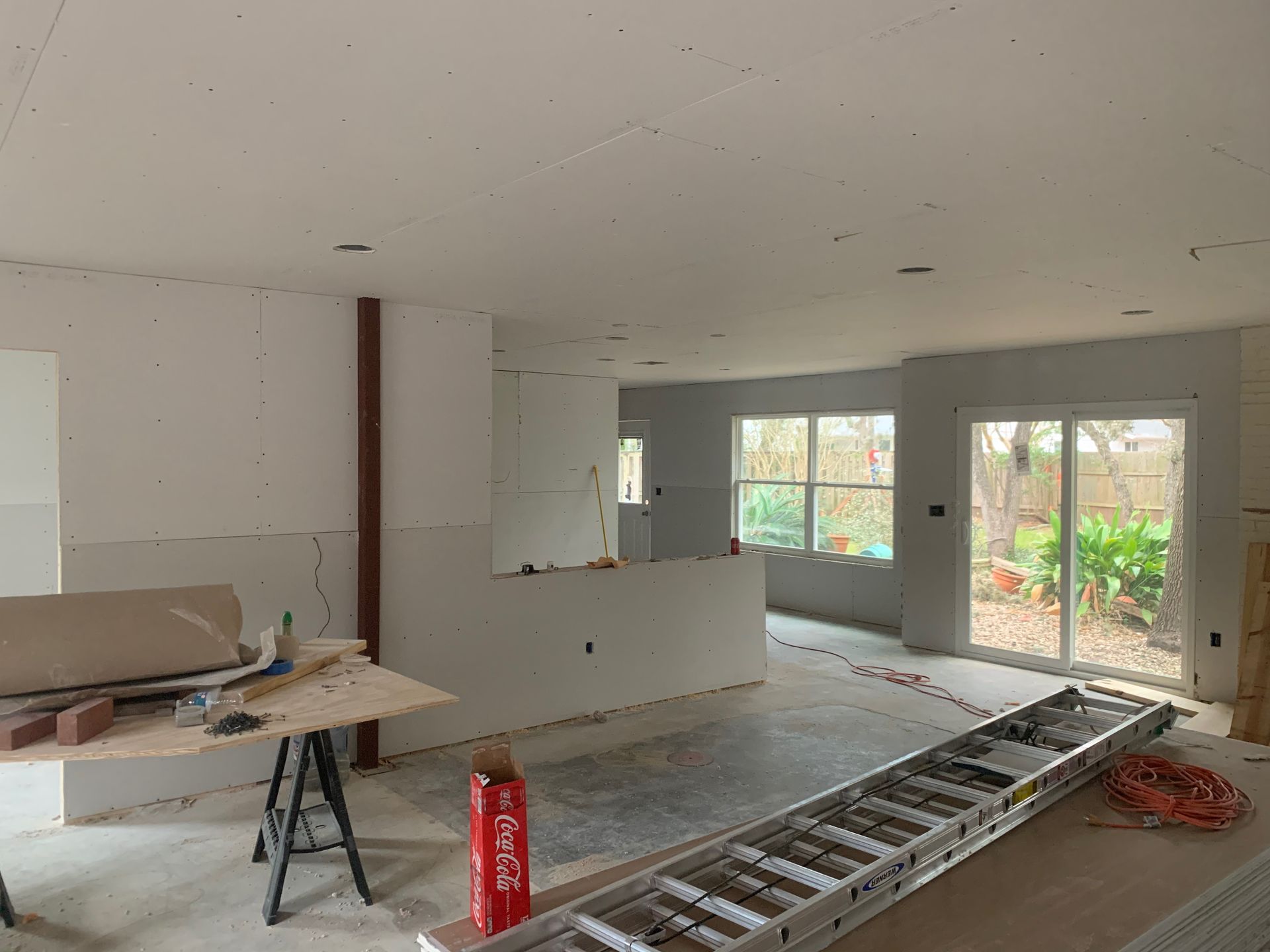 A ladder is sitting on the floor in a room under construction.