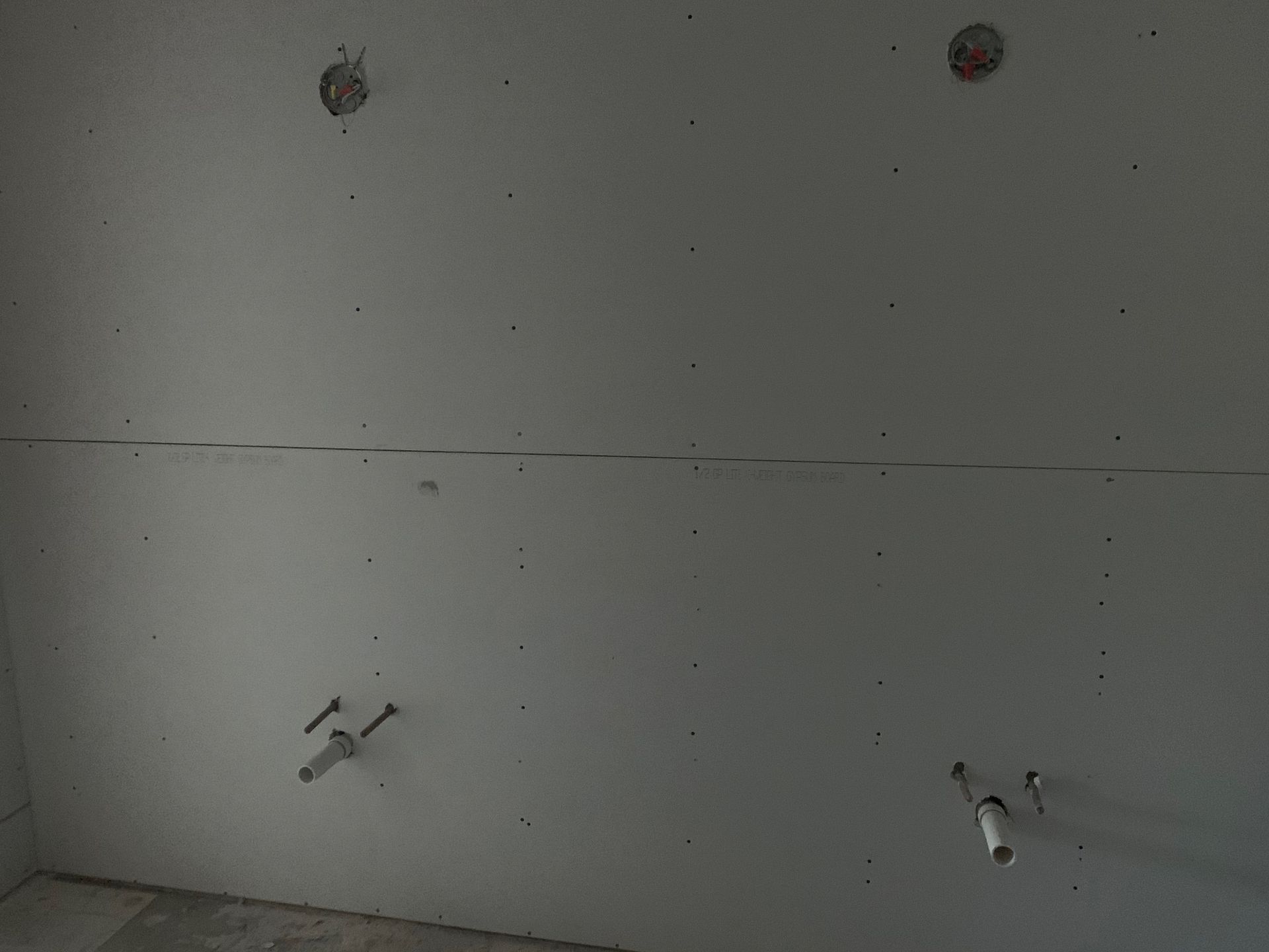 A bathroom under construction with a white wall and a sink.