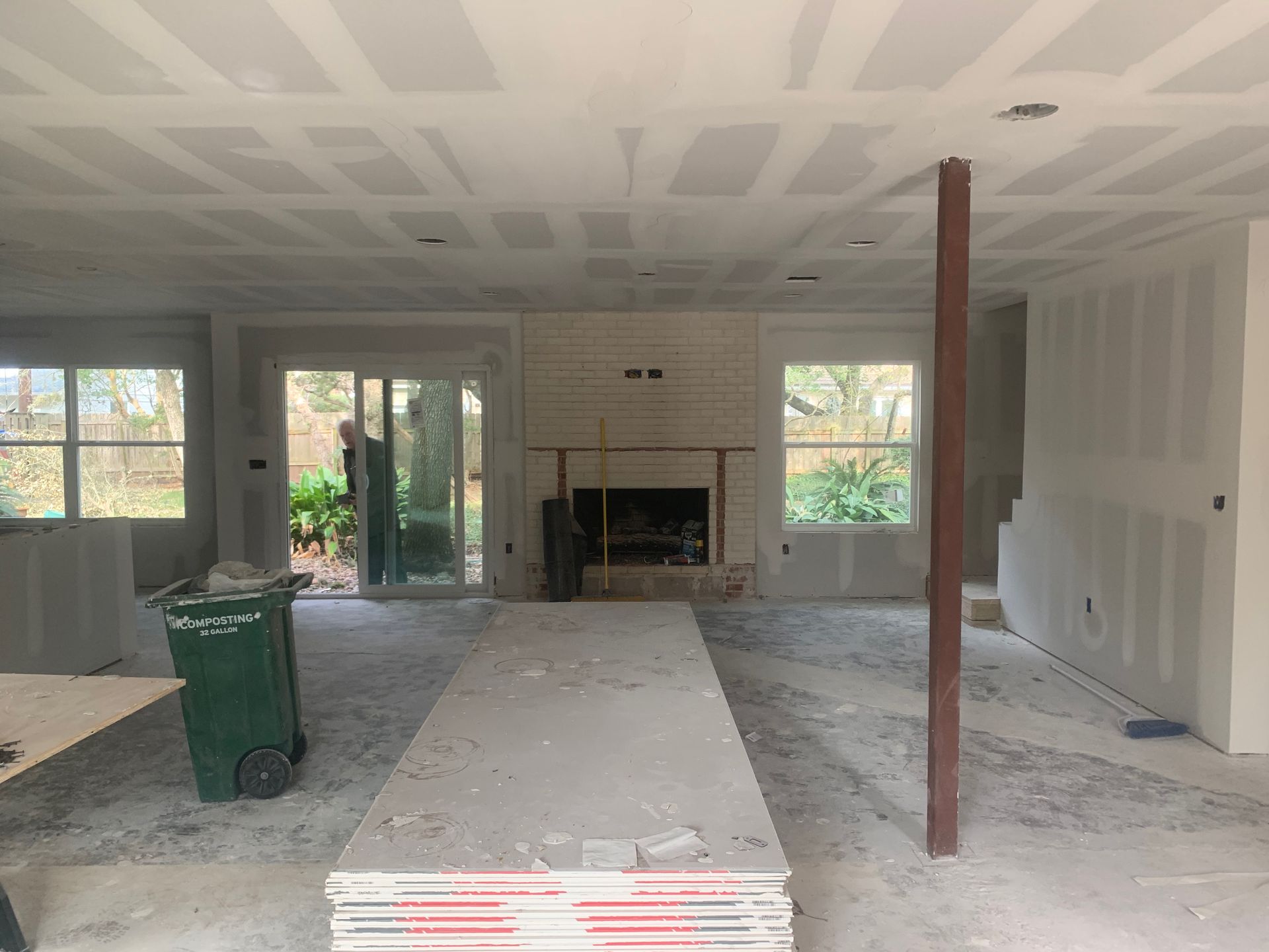 A large room with a fireplace and a trash can in it.