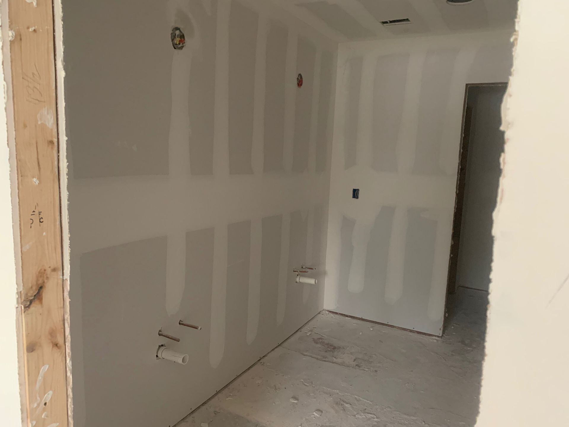 An empty room with drywall on the walls and a door.