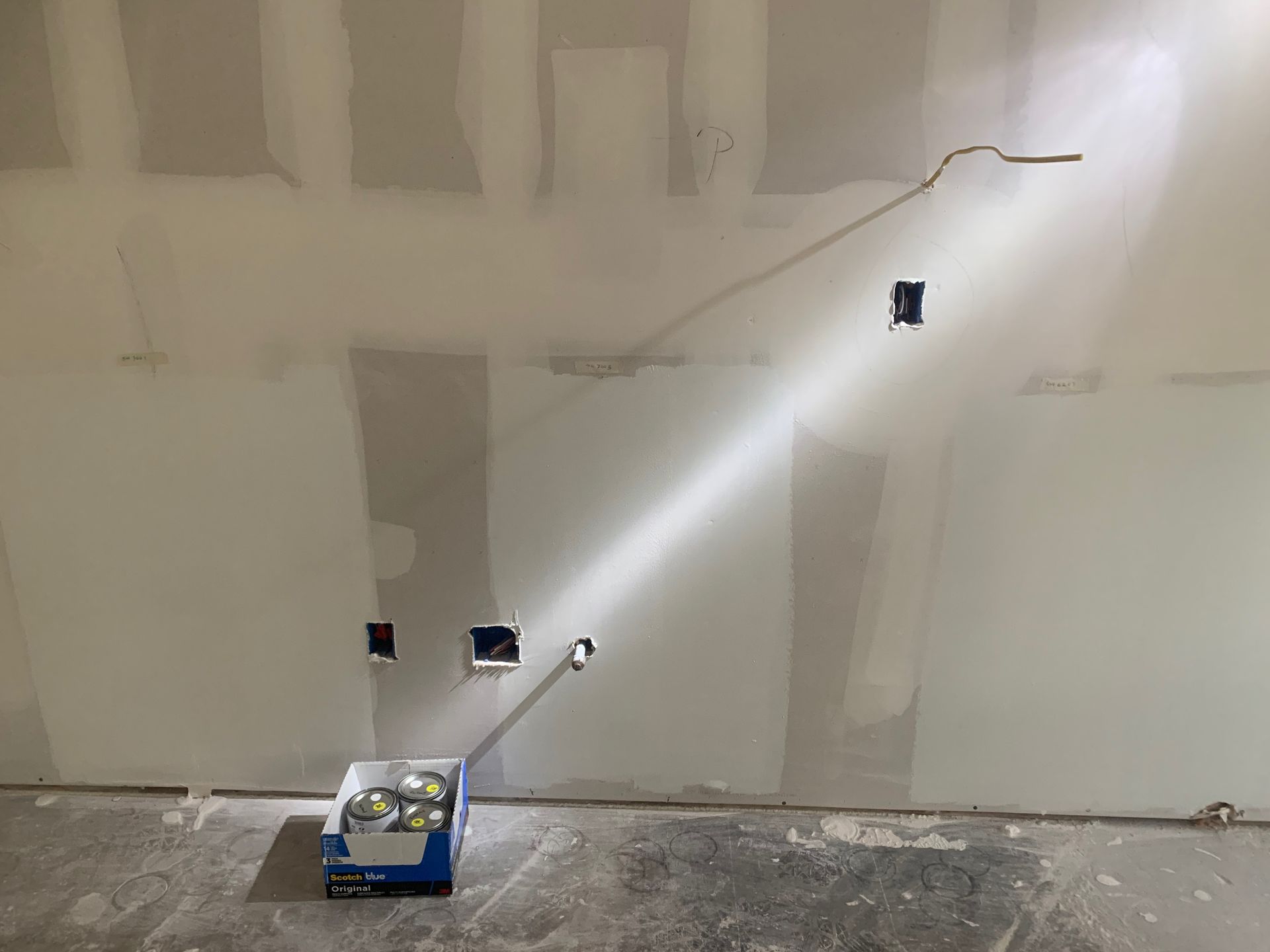 A box of tools is sitting on the floor next to a wall.