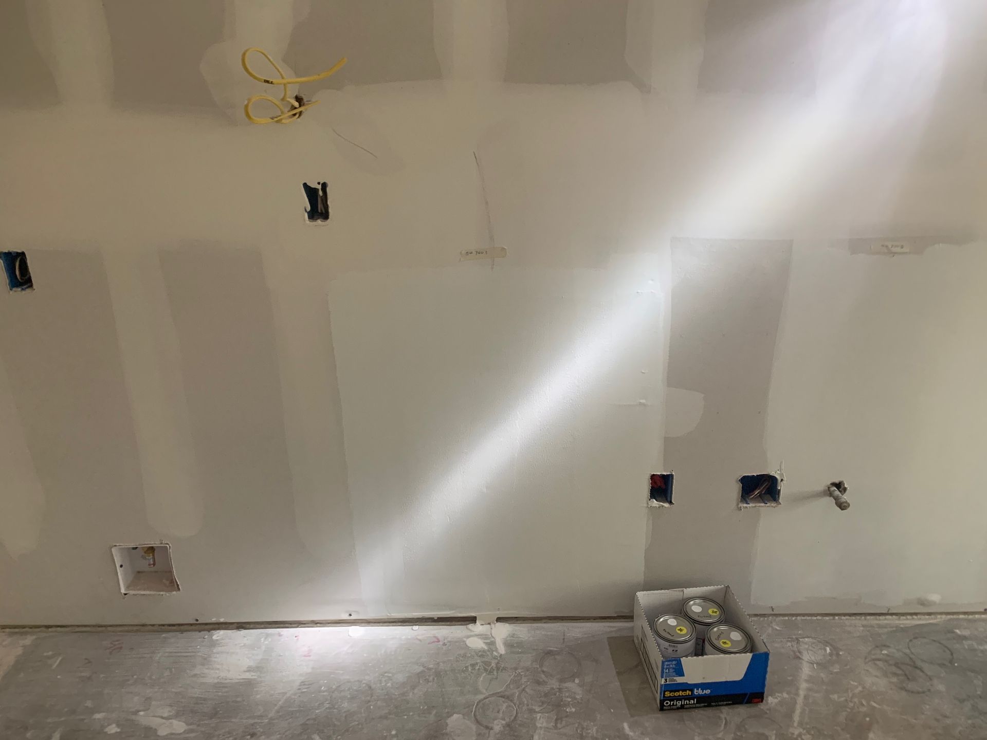 A box of cans is sitting on the floor next to a wall.