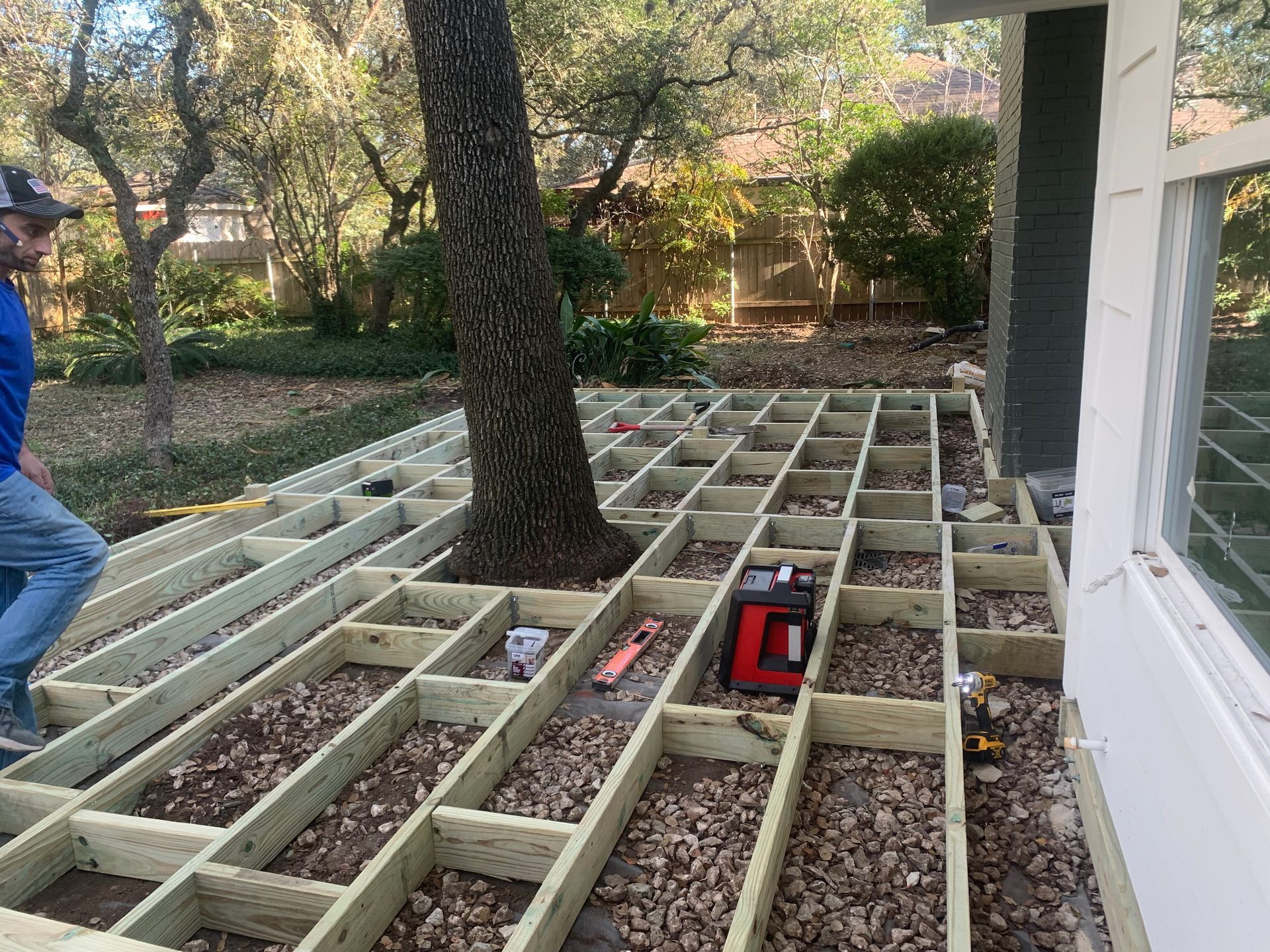 A man is standing on a wooden deck under construction.